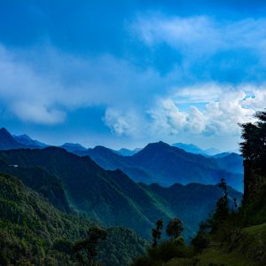 a view of a mountain range with trees and mountains in the background