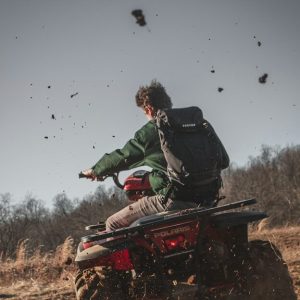 man riding red atv on brown field during daytime